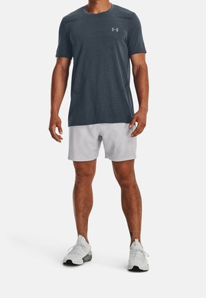 Dunkelgraues, kurzärmeliges Sportshirt mit strukturiertem Muster, kombiniert mit hellgrauen Shorts und weißen Sportschuhen.