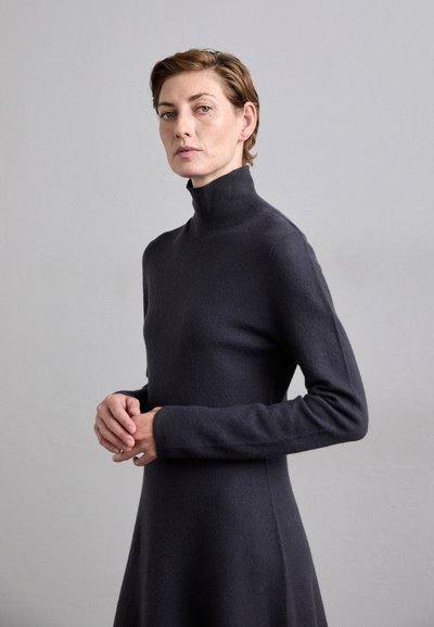 Dunkelgraues Strickkleid mit hohem Ausschnitt, langen Ärmlen und ausgestellter Silhouette. Weiche Textur mit minimalen Details.