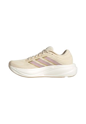 Beiger Laufschuh mit pinkfarbenen Streifen an der Seite, weißer dicker Sohle und Schnürverschluss, von der Außenseite gezeigt.