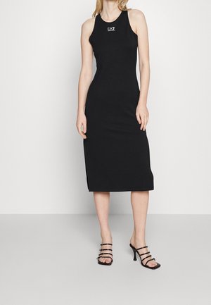 Schwarzes ärmelloses Midikleid mit figurbetonter Silhouette aus dehnbarem Stoff. Mit Logo auf der Brust und Seitenschlitzen. Kombiniert mit Riemchenabsätzen.