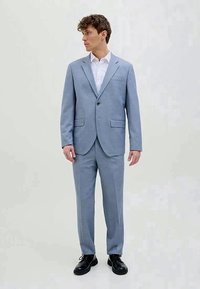 Fato azul claro feito de tecido texturizado, apresentando um corte ajustado, lapelas recortadas, fecho com um único botão e calças ajustadas.