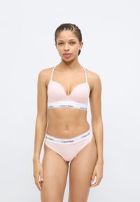 Φωτεινό ροζ σουτιέν με βαθύ ντεκολτέ και λεπτές τιράντες, σετ με μαγιό σλιπ που έχει λευκή μέση με το λογότυπο Calvin Klein.