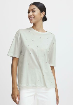 T-shirt verde chiaro con maniche corte, scollatura tonda e decorazioni argentate sparse sul davanti. Materiale in cotone morbido con vestibilità rilassata.