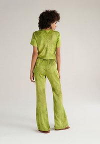 Set due in due pezzi verde tie-dye realizzato in tessuto morbido, composto da una maglietta a maniche corte e pantaloni a gamba larga con vita elastica.