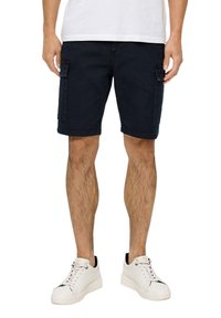 Granatowe szorty cargo z denimu, z bocznymi kieszeniami, z podwiniętymi brzegami i luźnym krojem, w zestawieniu z białymi trampkami.