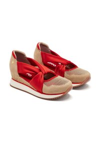 Zapatillas beige y rojas con una parte superior de malla transpirable, correas de tela roja anudadas y una media suela blanca en forma de cuña. Suela de goma texturada.