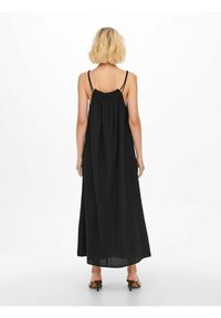 Robe maxi noire avec des bretelles fines et un décolleté froncé. Tissu léger et texturé qui descend jusqu'à la cheville. Design simple et minimaliste.