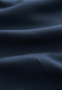 Tela de un azul oscuro con una superficie lisa y texturada, que presenta patrones sutiles y suaves pliegues, indicando un material ligero.
