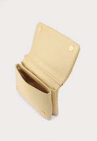 Μπεζ δερμάτινη τσάντα με διπλό καπάκι, χρυσές μεταλλικές λεπτομέρειες, μαγνητικό κούμπωμα και δύο διαμερίσματα, ένα με φερμουάρ.