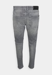 Šedé slim-fit džíny s vybledlým povrchem, dvě zadní kapsy a černou páskovou nášivkou; standardní délka s zúženými nohama.