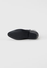 Scarpa in pelle nera con tomaia liscia, punta arrotondata e suola in gomma texturizzata caratterizzata da scanalature orizzontali per una buona aderenza.