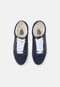 Marinblå mockaskor med vita snörningar, kontrasterande sömmar och en vit gummisula. Logotyp på innersulan och sidan. Klassisk låg toppdesign.