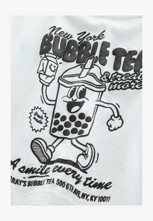 Mustvalge graafika naeratavast mulliteega tassist, kus on suured tapiokapärlid, hoides piimapakki, valgel särgil. Tekst sisaldab sõnu "New York BUBBLE TEA."