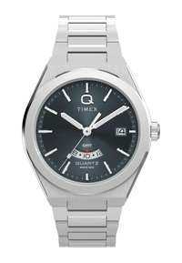 Montre à quartz Timex avec un bracelet en acier inoxydable, boîtier rond en argent, cadran gris foncé, index argentés et affichage de la date à 3 heures.