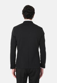 Giacca nera, vestibilità su misura, spacco singolo sul retro, maniche lunghe, polsini con bottone, texture liscia, rever classici, design minimalista.