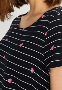 T-shirt en coton avec rayures bleu marine et blanches, orné de petites broderies de c53urs roses dispersE9es sur le tissu et dotE9 d'un col rond.