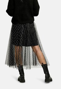 Čierna tylová sukňa so striebornými vzormi srdiečok, prekrytá čiernou spodnou sukňou. Nosí sa s čiernymi masívnymi čižmami.