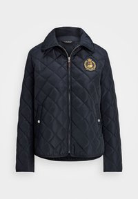 Veste matelassée bleu marine avec fermeture éclair à l'avant, col et poches latérales ; elle présente un emblème brodé sur la poitrine gauche. Matière en nylon lisse.