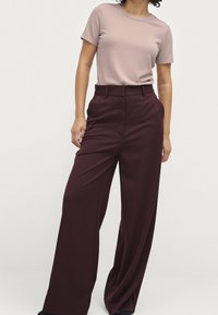 Jasnoróżowa prążkowana koszulka i szerokie buraczkowe spodnie, z wysokim stanem i gładką, płynącą teksturą.