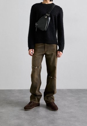 Person wearing a black textured sweater, olive ripped wide-leg jeans, brown shoes, and a black crossbody bag with silver zipper details.