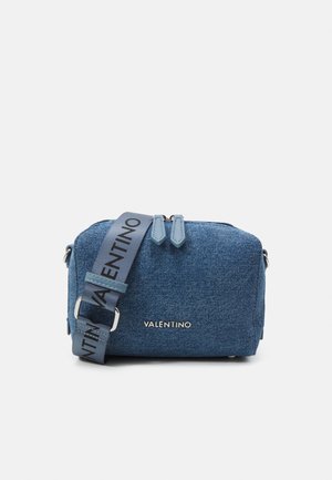 Blauwe denim crossbodytas met dubbele ritssluiting, brede verstelbare schouderband bedrukt met "Valentino" en zilveren Valentino-logo aan de voorkant.