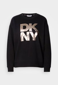 Svart hettegenser med en stor, slitt metallisk gull "DKNY" logo. Lange ermer og ribbestrikkede mansjetter med avslappet passform.