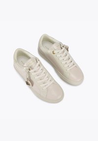 Beżowe skórzane sneakersy z teksturowanymi akcentami, płaskimi białymi sznurowadłami, złotym oczkiem i detalem logo na języku; płaska gumowa podeszwa.