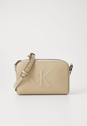 Beige rektangulær crossbody taske med justerbar rem og præget "cK" logo foran mod hvid baggrund.