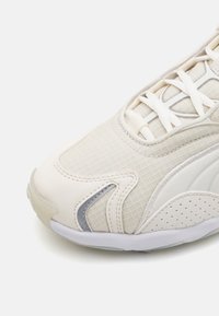 Baskets beige clair avec tige texturée, motif à carreaux, lacets blancs et accents gris. Dispose d'une semelle en caoutchouc lisse avec perforations pour la respirabilité.