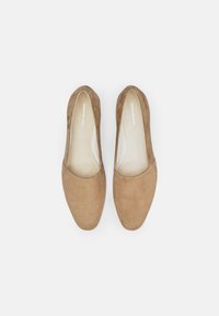 Barna nubuk slip-on cipők kerek orral, sima belső béléssel és minimalista dizájnnal, amelyek tiszta, klasszikus esztétikát kínálnak.