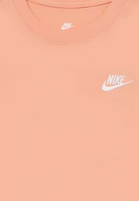 Nike őszibarack színű póló kerek nyakkivágással és fehér logóval. Simaságával és puha textúrájával készült.