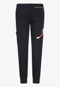 Calças de moletão pretas feitas de algodão, com um design gráfico em vermelho e branco de um lado, cintura elástica e bolso tipo cargo.