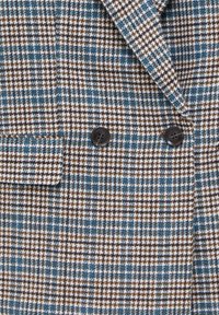 Blazer à motif pied-de-poule marron, bleu et blanc, avec deux boutons noirs et un revers plié.