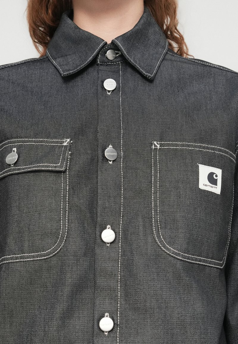 Grå denimskjorte med spidst krave, forlommer, trykknapper og kontrastfuld hvid syning. Brandlogo på venstre lomme.