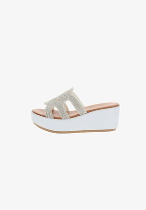 Sandale compensée blanche à plateforme avec semelle couleur cuir et brides ornées de strass scintillants formant un motif découpé sur le dessus.