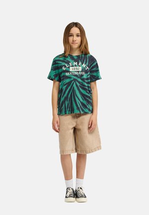 Zielono-czarny t-shirt tie-dye z napisem "ELEMENT 1992 SKATEBOARDS", zestawiony z beżowymi szortami dżinsowymi i czarnymi sneakersami z białymi podeszwami.