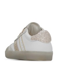 Baskets blanches avec détail scintillant au talon rose, accents beige texturés, surpiqûres dorées et semelle en caoutchouc. Le design présente un style classique basse.