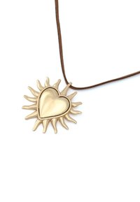 Pendentif doré en forme de soleil avec un cœur au centre, accroché à un cordon en cuir marron. Surface lisse, finition légèrement réfléchissante.