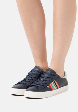 Navy leather sneakers featuring colorful striped accents, white rubber sole, and round toe design. Laced front with a low-top profile.