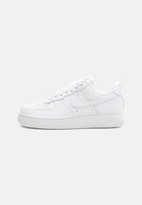 Lave topp hvite lær sneakers med perforert tå, hvite snører og tykk såle med "AIR"-merke på siden.