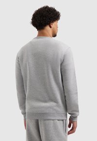 Grijze sweatshirt gemaakt van zacht stof met een ronde halslijn, geribbelde manchetten en zoom. Het ontwerp heeft een gladde, effen textuur.