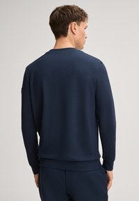 Navy blue pullover sweatshirt with long sleeves, ribbed cuffs and hem, smooth texture, and minimalist design without front details.
