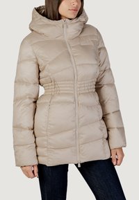Giacca a vento beige con vita aderente, colletto alto e chiusura con zip frontale. Presenta un motivo a coperte orizzontali e tasche laterali.