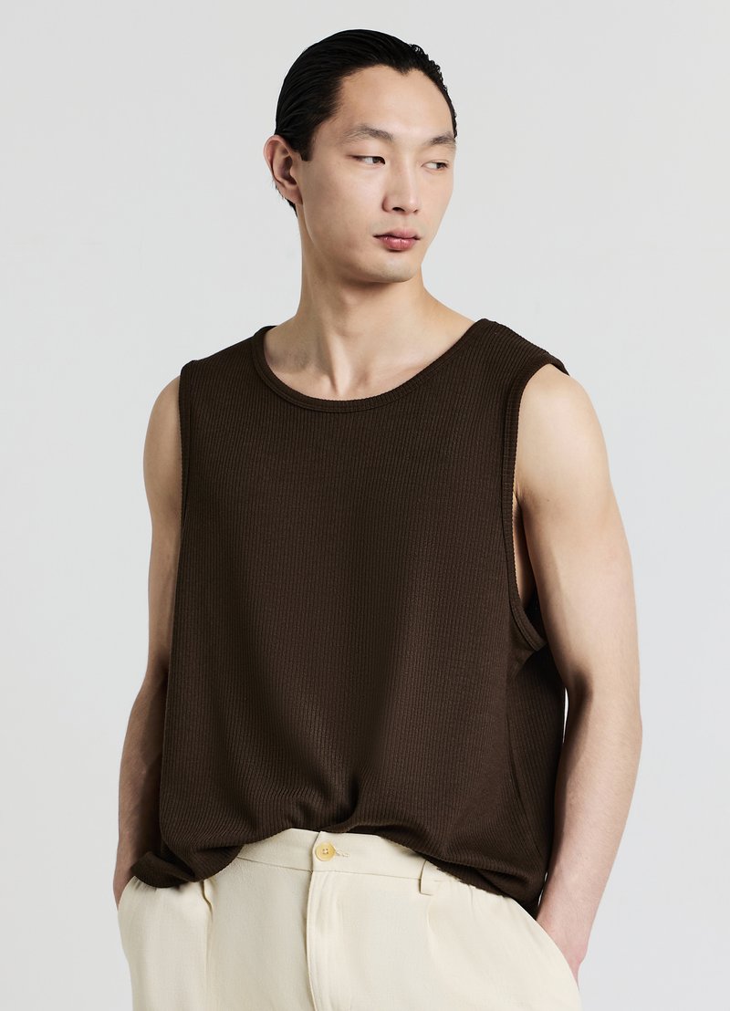 Débardeur marron à côtes avec un large col rond et sans manches, présenté avec un pantalon clair. Texture douce.