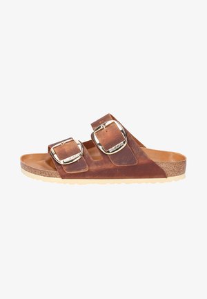 Bruine leren sandalen met twee brede banden, voorzien van zilveren gespen. Kurken voetbed met een beige rubberen zool. Glad textuur en open ontwerp.