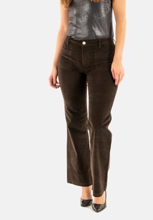 Pantalones de pana marrón con un diseño de pierna recta, cuentan con bolsillos frontales y un botón de tono dorado. Combinados con tacones altos negros.