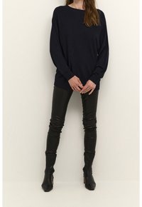 Navy knitted sweater with long sleeves paired with fitted black leather pants and heeled black ankle boots, showcasing a sleek silhouette.