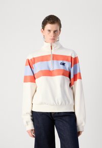 Hvit zip-up hettegenser med horisontale striper i rødt, lys blått og korall. Logo på venstre bryst, med ribbestrikkede mansjetter og kant.