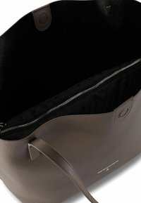 Bolso tote de cuero marrón con textura granulada, abertura superior y interior negro con bolsillo con cremallera y logo de la marca en el lateral.