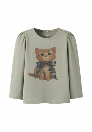 Long-sleeve light green shirt with puffed shoulders, featuring a brown kitten wearing a large floral pattern bow at the center front.